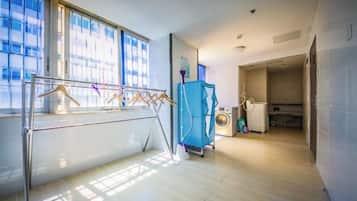 Habitació amb finestra gran, estendal, rentadora i zona de cuina.