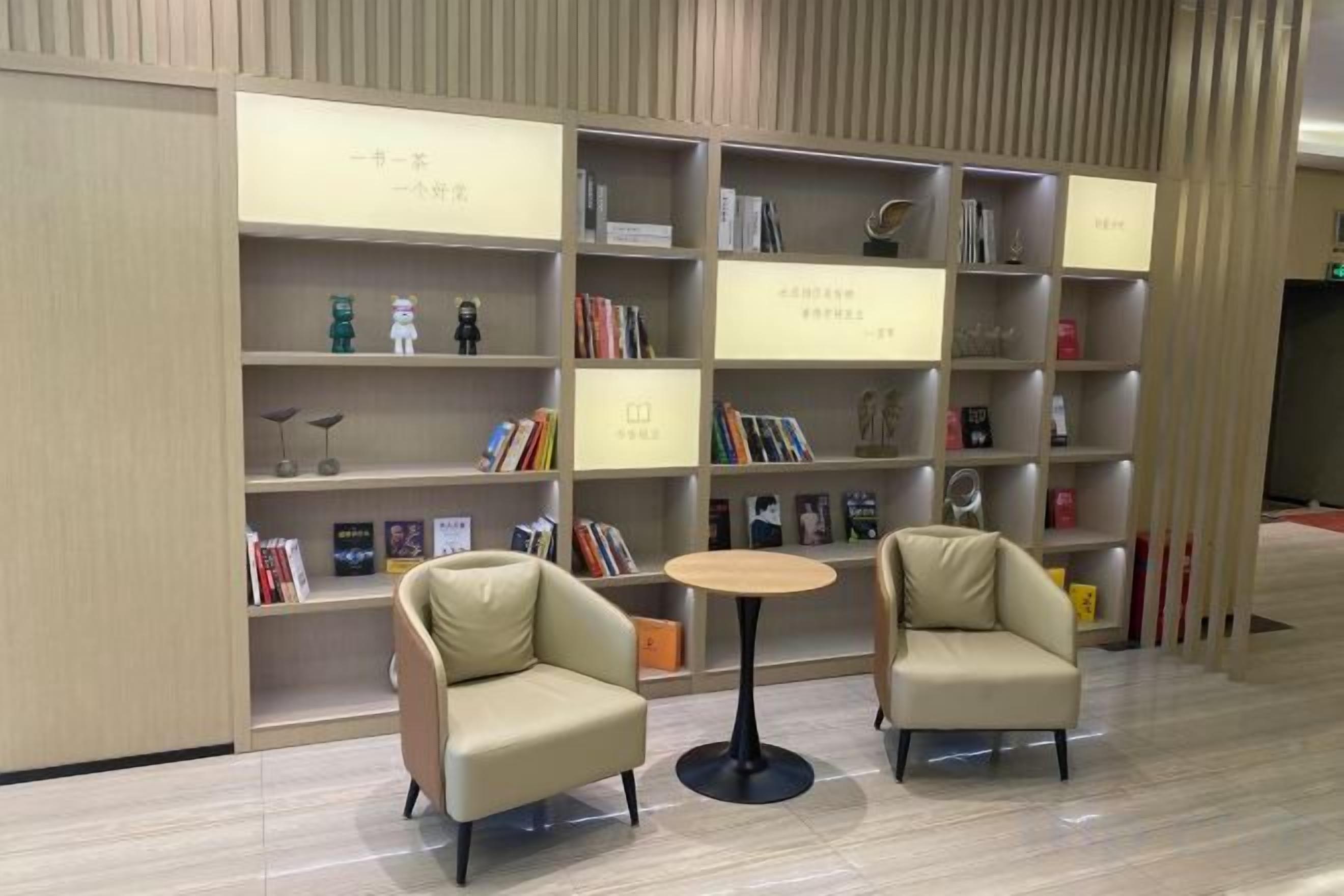 Una biblioteca con scaffali, due poltrone e un piccolo tavolino rotondo.