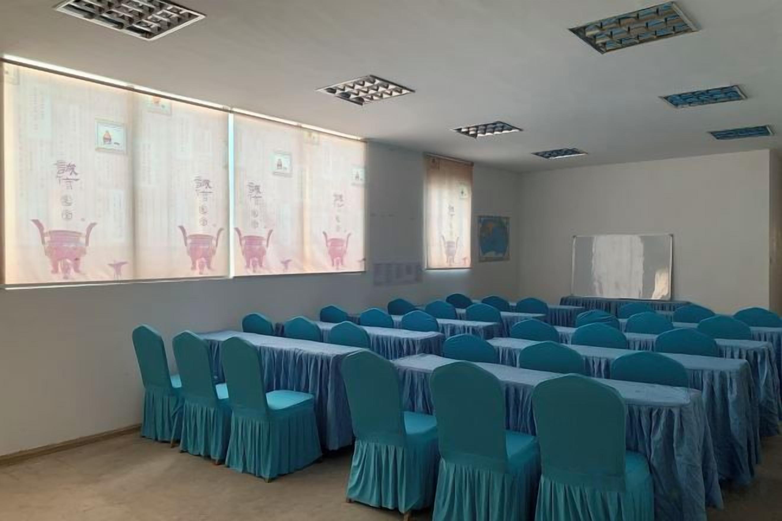 Ein Konferenzraum mit Tischen und Stühlen, großen Fenstern mit Kunstwerken und Deckenlüftungsschlitzen.
