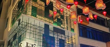 A building with a sign that reads 'Huang Ping' and a series of red lanterns hanging above.