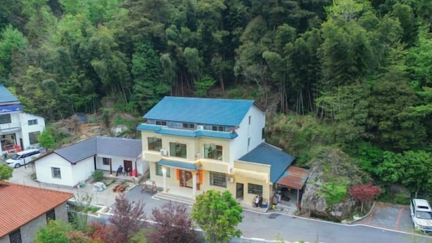 Un edificio de dos pisos con techo azul, rodeado de un bosque frondoso.