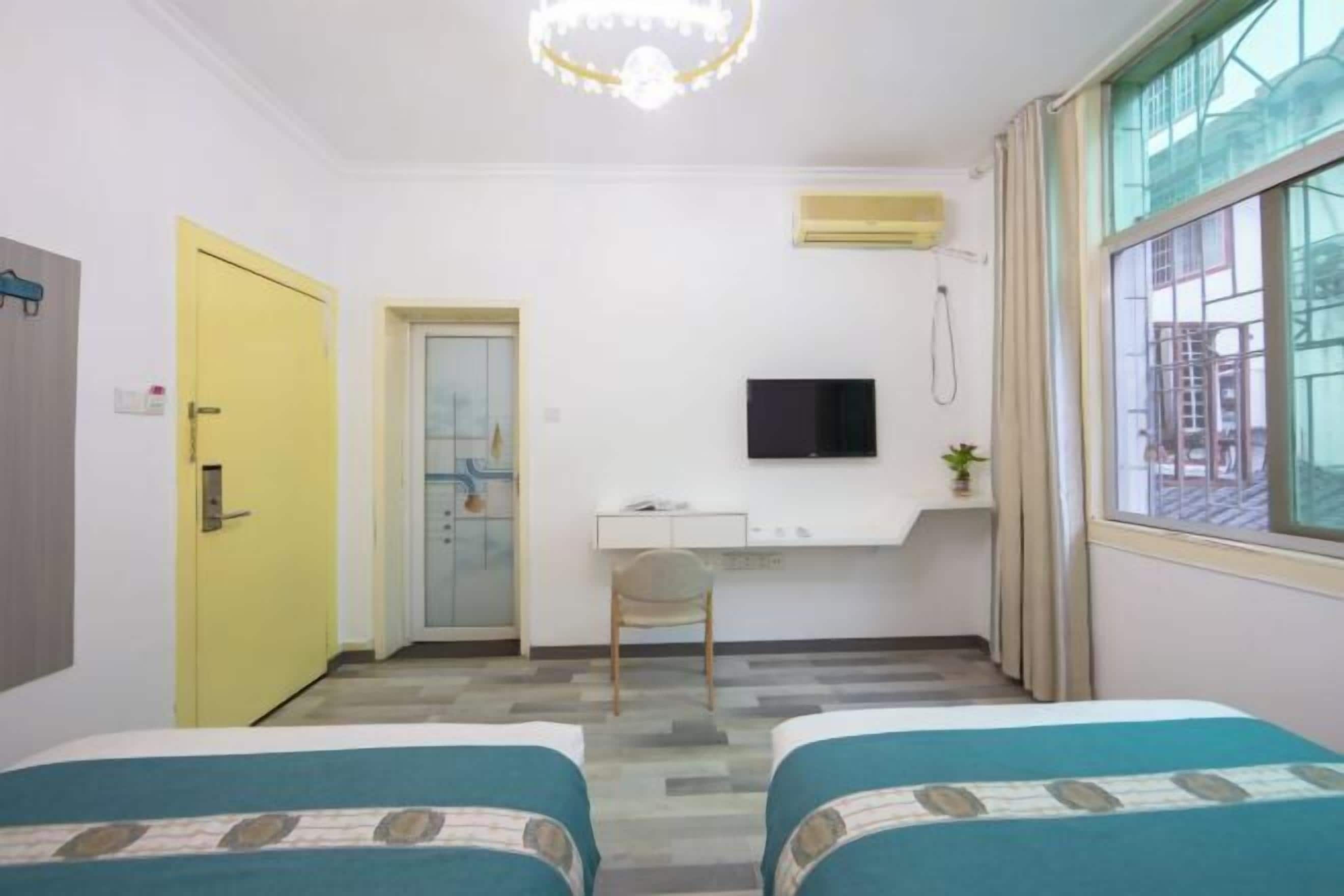 Habitación de hotel con dos camas, un escritorio, un televisor y una ventana con cortinas.