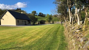 A house with a sloped roof and a well-maintained lawn. - Charming 3-bedroom bungalow in Kenmare with WiFi access (Kenmare)
