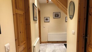 A hallway with wooden doors, framed pictures on the walls, a radiator, and a tiled floor. - Charming 3-bedroom bungalow in Kenmare with WiFi access (Kenmare)