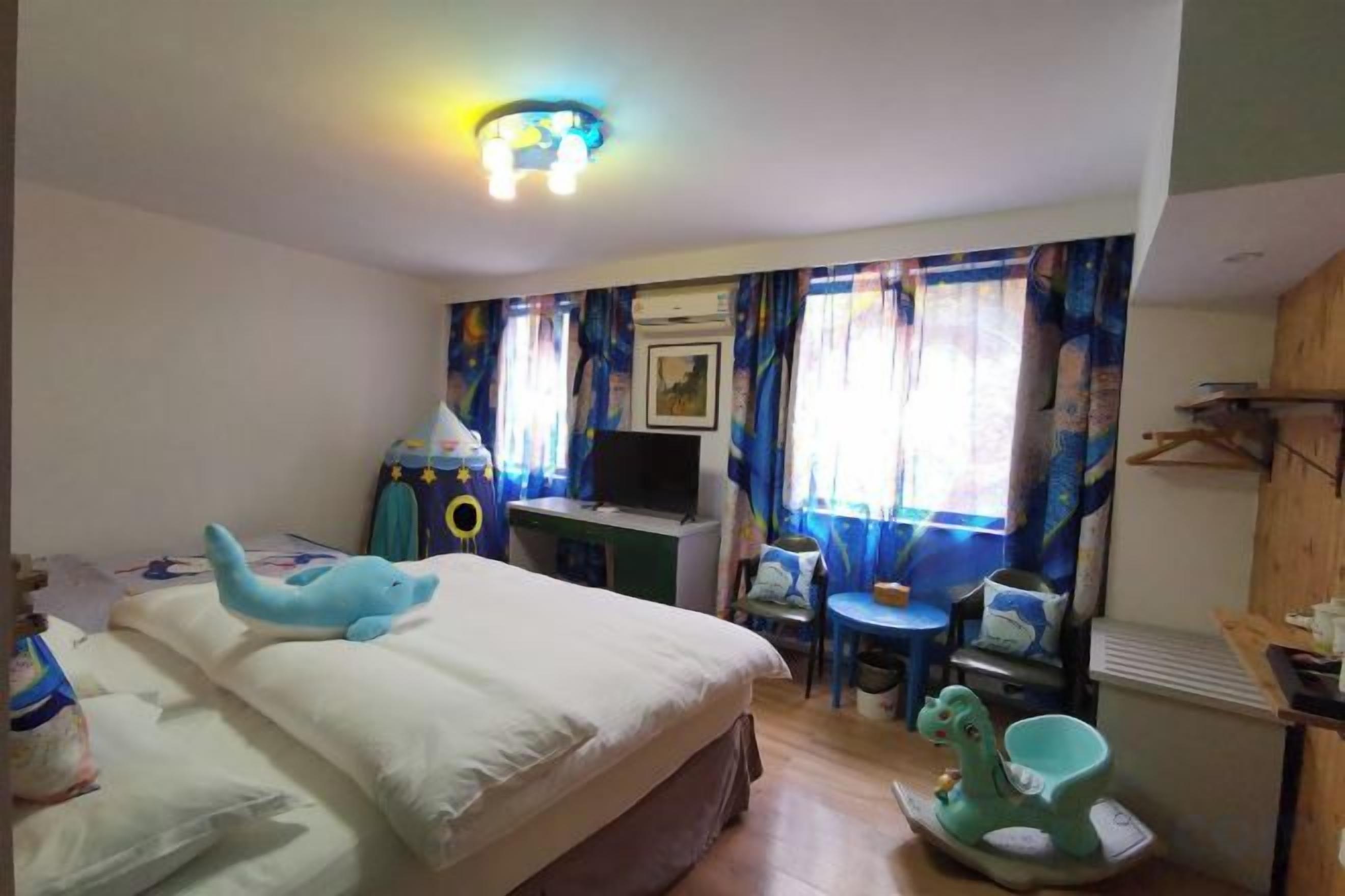 A hotel room with a bed, a desk, a chair, a television, and a window with curtains.