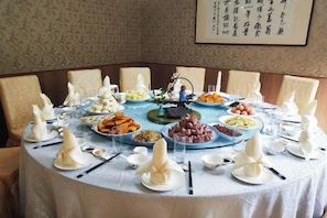 A round dining table with various dishes, plates, and chopsticks arranged for a meal. - Yuyao 702 Resort (Yuyao)