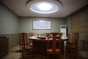 Une salle de conférence équipée d’une table ronde, de chaises, d’un écran de projection affichant du texte et d’un appareil de climatisation.