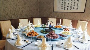 Una mesa de comedor redonda con varios platos y cubiertos, rodeada de sillas.