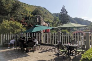 Un espace extérieur aménagé avec des tables et des chaises, une clôture blanche en bois et une chaîne de montagnes en arrière-plan.