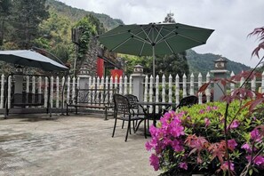 An outdoor patio with a table and chairs, a green umbrella, and a white picket fence. - Yuyao 702 Resort (Yuyao)