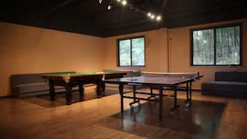 A room with a pool table, a ping pong table, and a sofa.