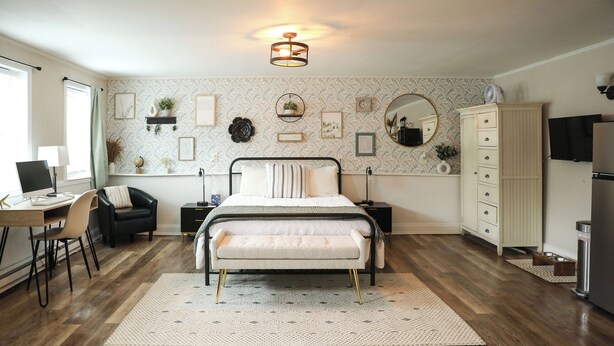 A bedroom with a bed, bedside tables, a desk, a chair, a wardrobe, a mirror, and a television.