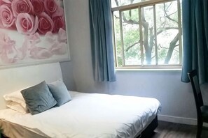 A bedroom with a bed, a window with curtains, and a wall with a floral painting. - Jiangbin Hotel (Shaoxing)