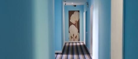 A hallway with blue walls and a striped carpet.