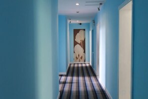 En hall med blå väggar och en randig matta.