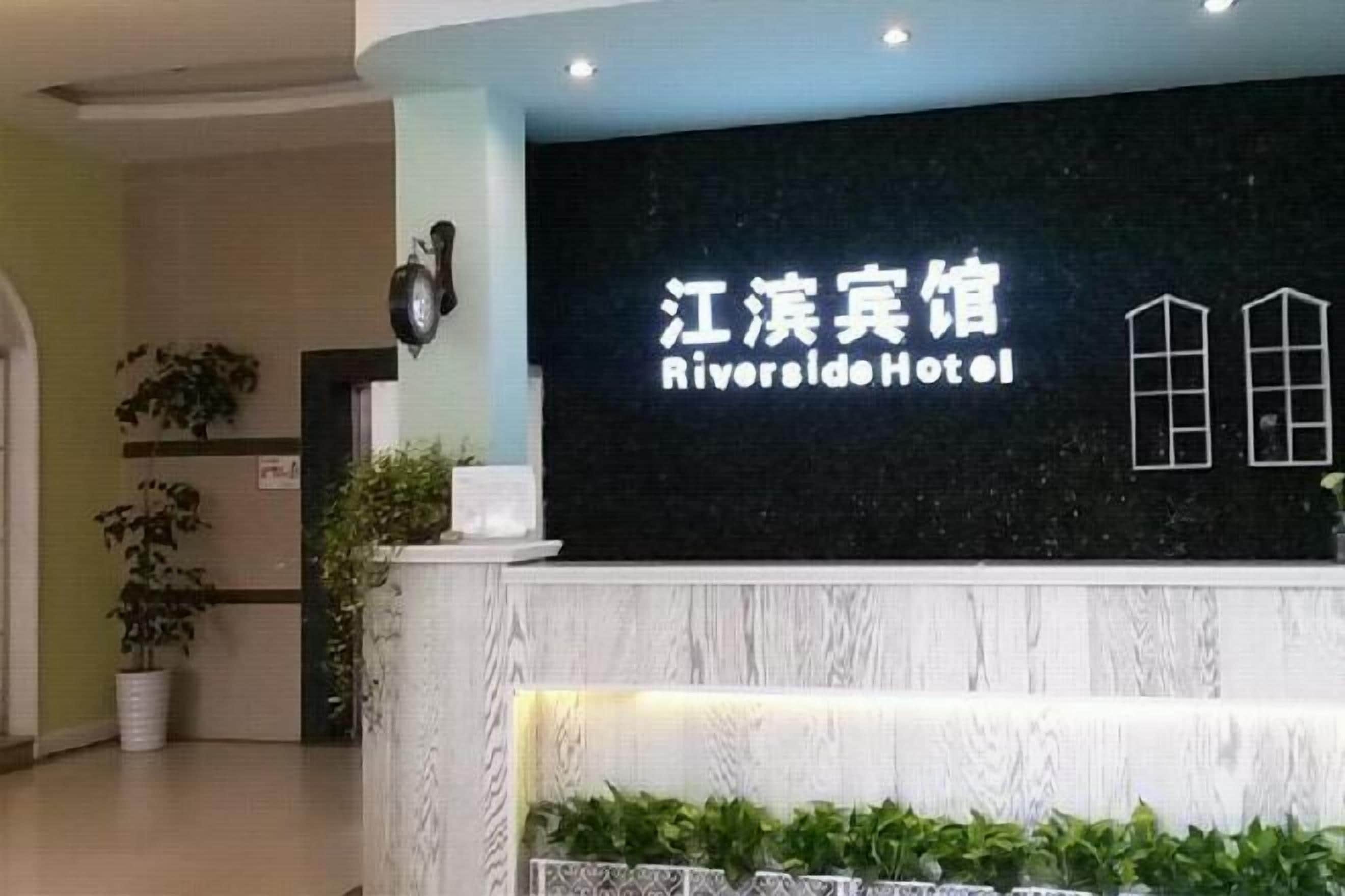 A hotel reception desk with a sign that reads 'Riverside Hotel.'