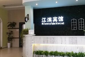 A hotel reception desk with a sign that reads 'Riverside Hotel.'