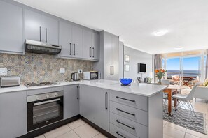 A modern kitchen with grey cabinets, a built-in oven, a microwave, and a large island with a blue bowl.