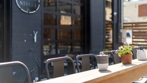 An outdoor seating area with a wooden table and chairs, a potted plant, and a sign reading "PEACH STREET". - Historic Boutique Inn, The Byrum Room 2A, Downtown Tellico Plains (Tellico Plains)