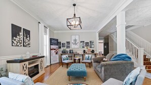 A spacious living room with a fireplace, comfortable seating, and a staircase leading to another level. - Historic Boutique Inn, The Byrum Room 2A, Downtown Tellico Plains (Tellico Plains)