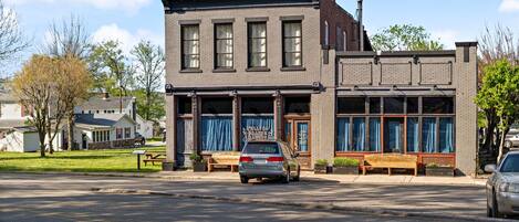 Een gebouw met twee verdiepingen, een bakstenen gevel, grote ramen en een bord waarop staat dat het een restaurant is.