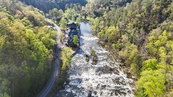 Vista aérea de un río con una carretera serpenteando a su lado, rodeado de un bosque denso.