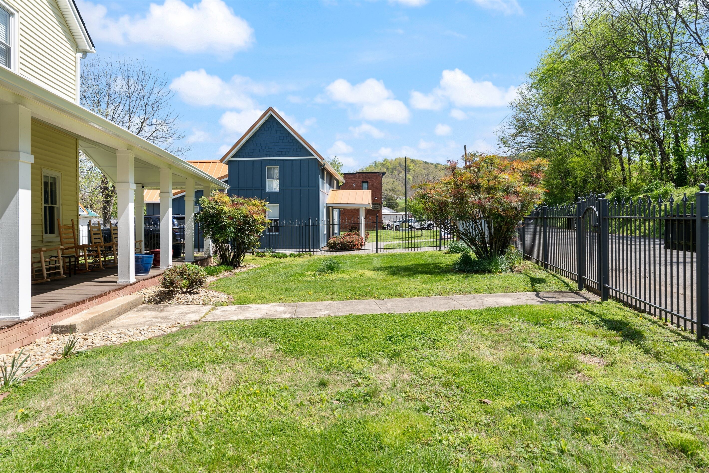 A residential property with a covered porch, a blue house, and a fenced yard.