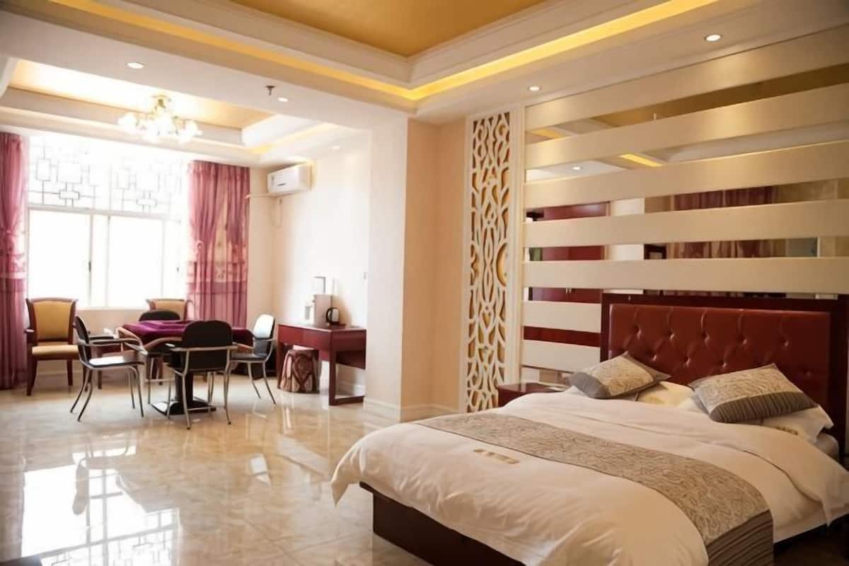 A bedroom with a large bed, a desk, and a chair.