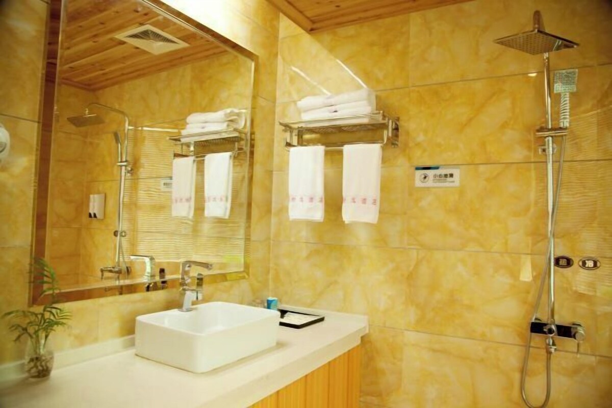 A bathroom with a white sink, a mirror, a shower, and towels on a rack.