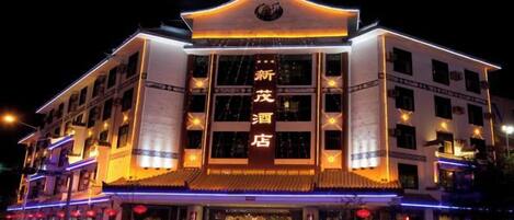 A multi-story hotel with illuminated signage and traditional architectural design.