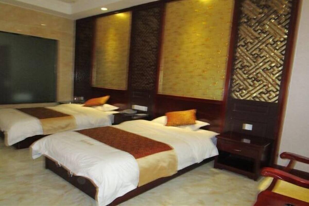 A hotel room with two beds, a wooden headboard, and a nightstand.