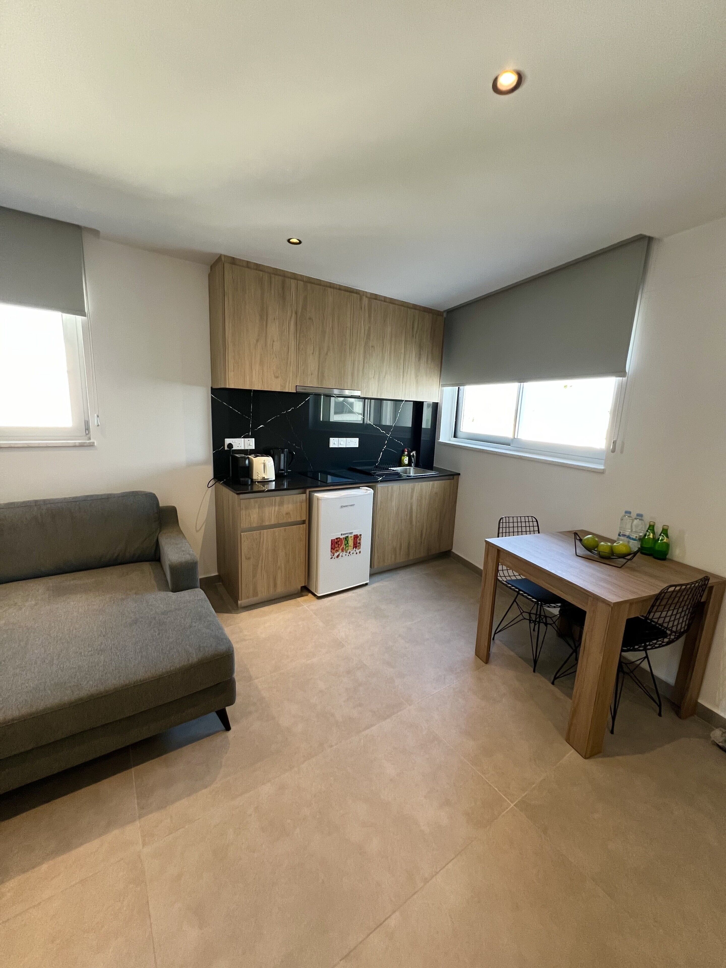 Una cocina compacta con refrigerador, una mesa de comedor con sillas y un sofá.