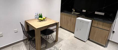 A modern kitchen with wooden cabinets, a black countertop, and a small refrigerator.