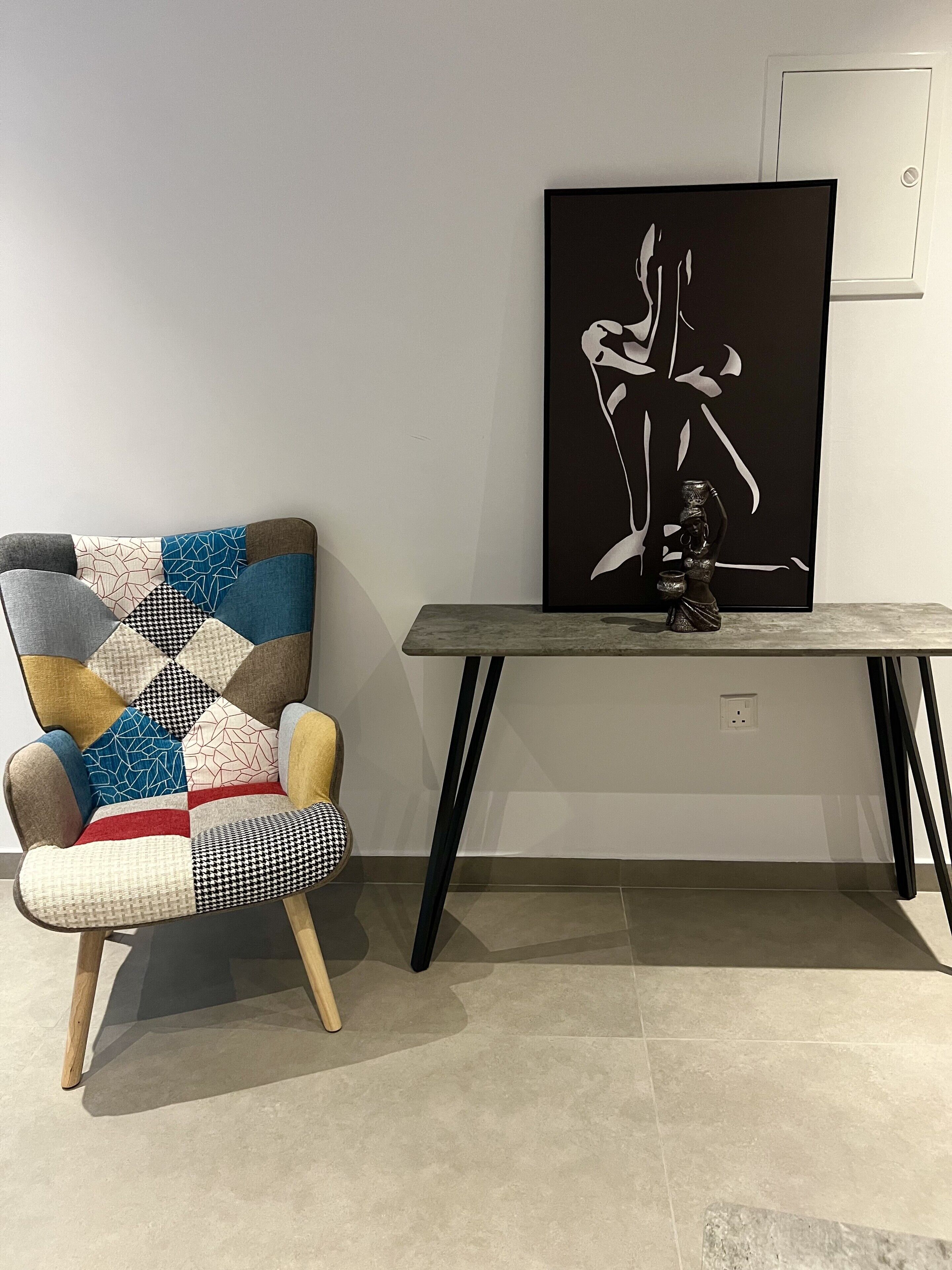 Una habitación moderna con un sillón estampado, una mesa minimalista y un cuadro abstracto grande.
