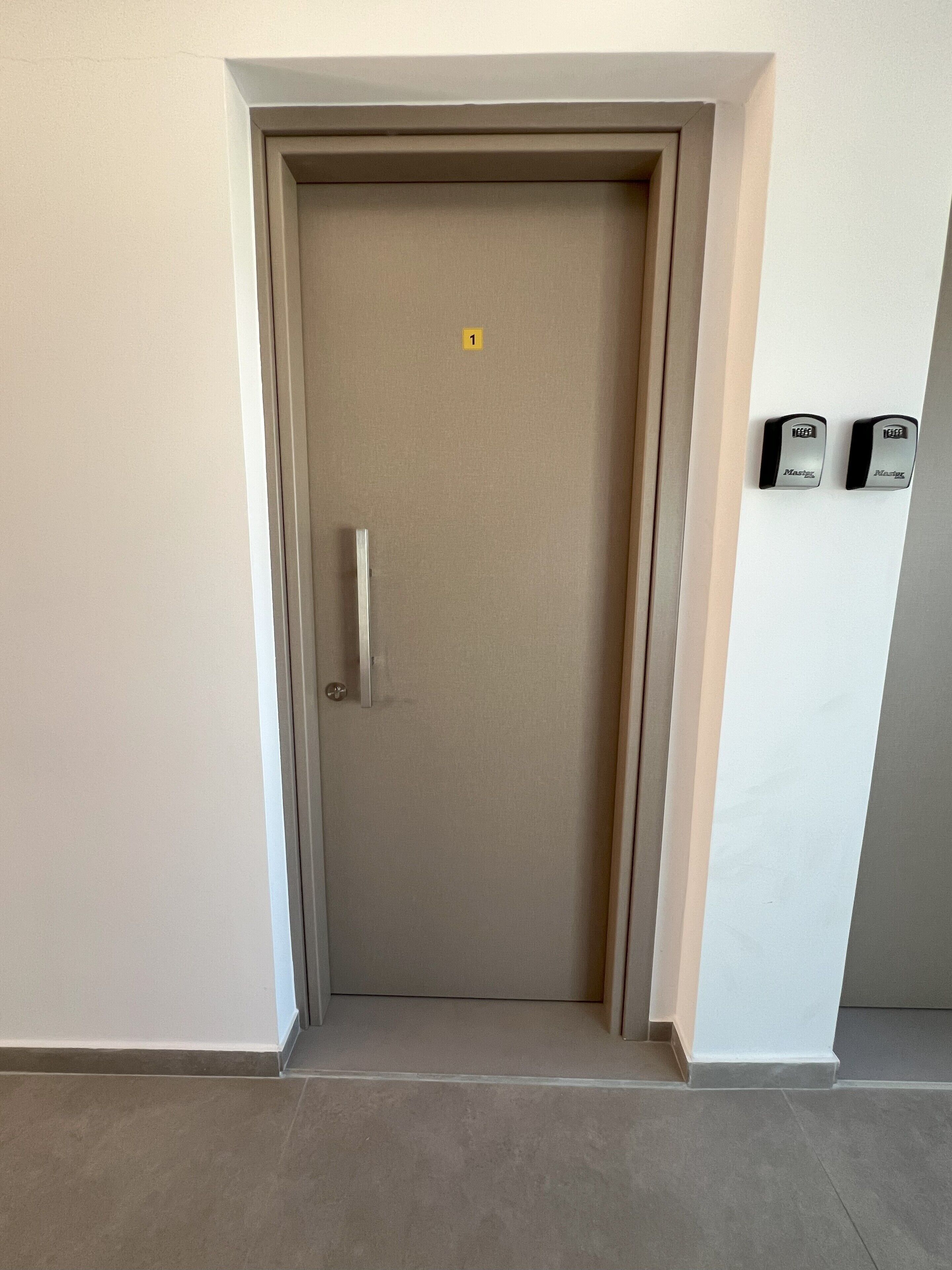 A closed door with a metallic handle and a small yellow sign above it.