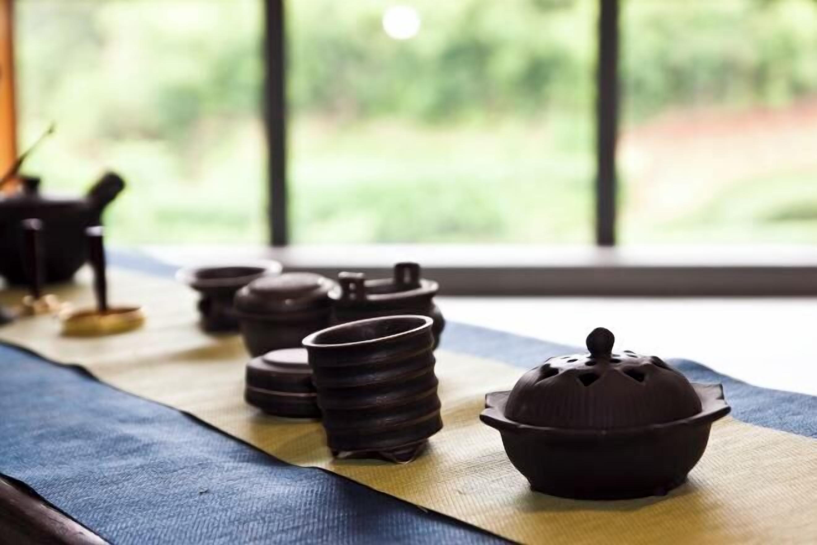 Un juego de té tradicional sobre un esterilla de tatami, con vistas a la vegetación.