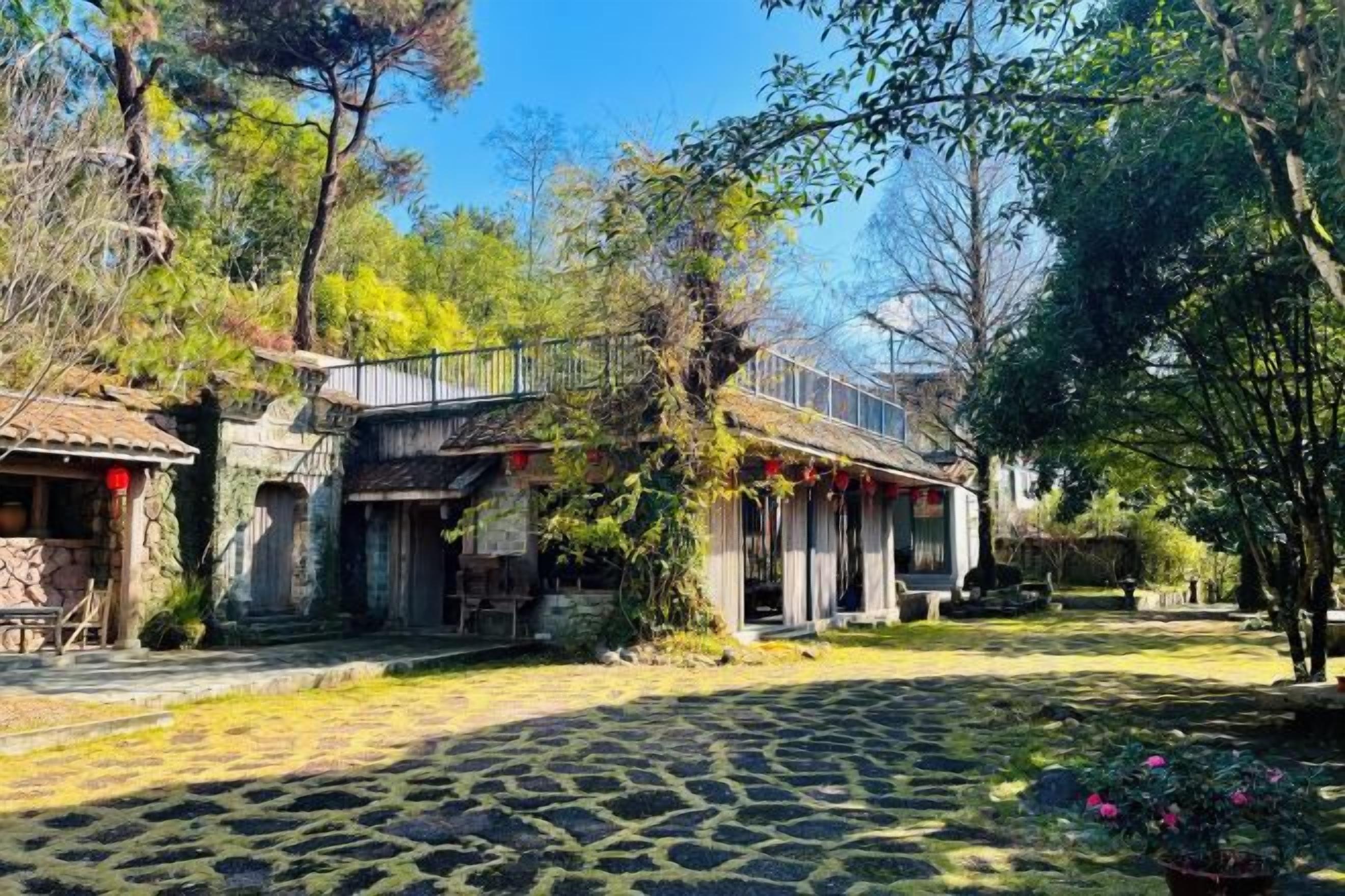 Un patio con suelo de adoquines, edificios de piedra y una valla de madera.