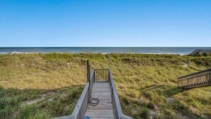 A wooden boardwalk leading to a beach with a clear view of the ocean.