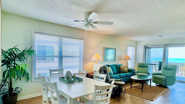 A living room with a dining table, chairs, a sofa, and a ceiling fan.