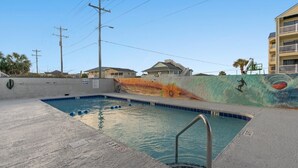 A swimming pool with a mural on the wall, a lifeguard stand, and a 3 FT depth marking.