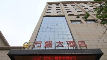 A tall building with a large glass facade and a sign with red Chinese characters.