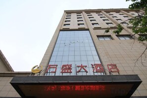 A tall building with a large glass facade and a sign with red Chinese characters. - Wansheng Hotel (Yuanqu)