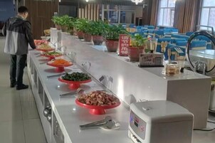 A buffet line with various food options and a person standing at the end.