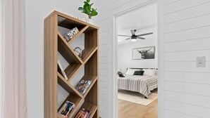 A hallway with a wooden bookshelf, a ceiling fan, and a bed with a striped blanket. -  - HIDDEN GEM - Spacious, minimal and clean! Legoland + Disney (Wahneta)