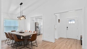 A modern kitchen with a stainless steel refrigerator and a dining area with a wooden table and chairs. -  - HIDDEN GEM - Spacious, minimal and clean! Legoland + Disney (Wahneta)