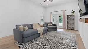 A modern living room with a grey sectional sofa, a patterned rug, and a ceiling fan. -  - HIDDEN GEM - Spacious, minimal and clean! Legoland + Disney (Wahneta)