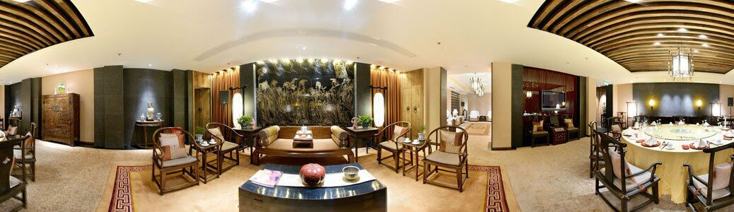 A spacious hotel lobby with a round table, seating arrangements, and a large wall mural.