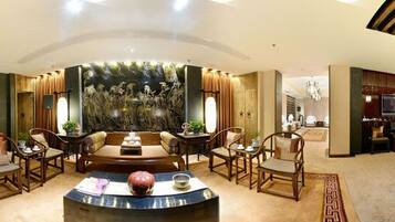 A spacious hotel lobby with a round table, seating arrangements, and a large wall mural.