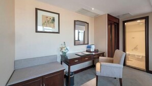 A hotel room with a desk, chair, a mirror, a framed picture, and a sliding door leading to a bathroom. - Bell Tower Hotel (Xi'an)