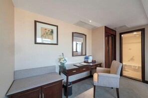 A hotel room with a desk, chair, a mirror, a framed picture, and a sliding door leading to a bathroom. - Bell Tower Hotel (Xi'an)